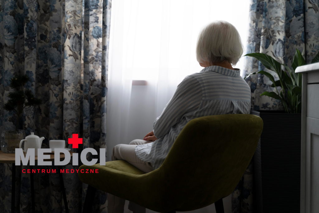 Starsza osoba siedzi na fotelu i patrzy przez okno - taki brak aktywności fizycznej może skutkować sarkopenią